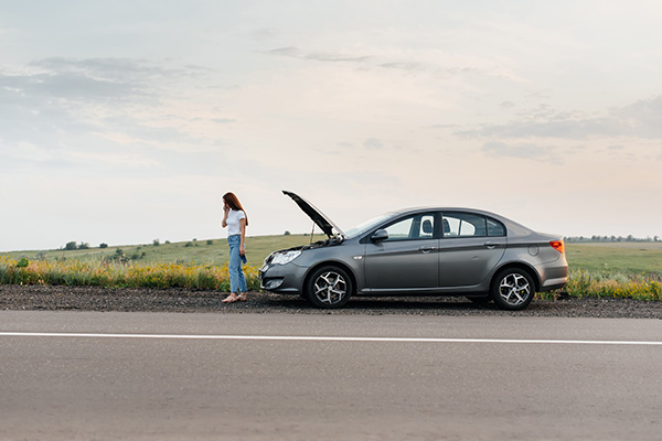 Car Breakdown Woman standing beside a broken-down car on the roadside.