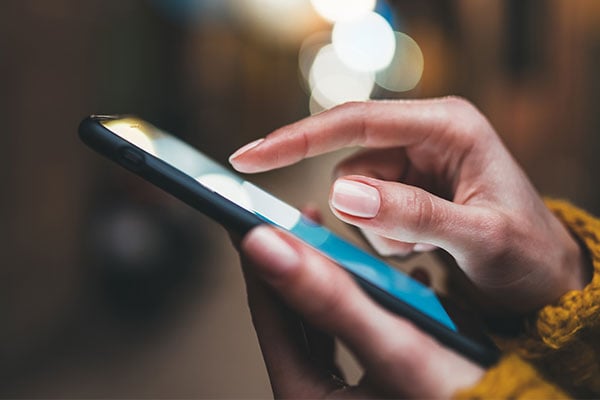 Hand holding a smartphone while scrolling on the screen.