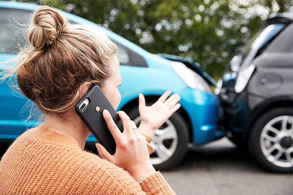 Accident Call A woman making a phone call near two cars involved in a minor accident.