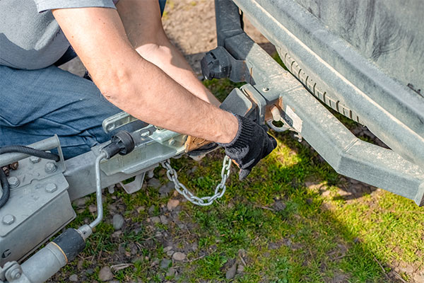 Trailer Hitching A person securing a trailer hitch to the back of a vehicle.