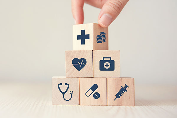 Wooden blocks stacked with icons representing healthcare and wellness.