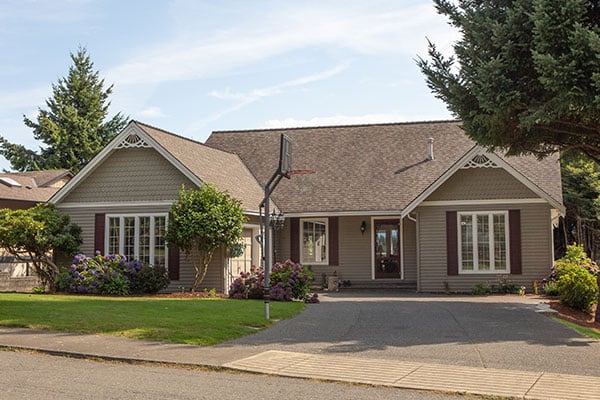 A single-story home with a front porch, landscaping, and a driveway.