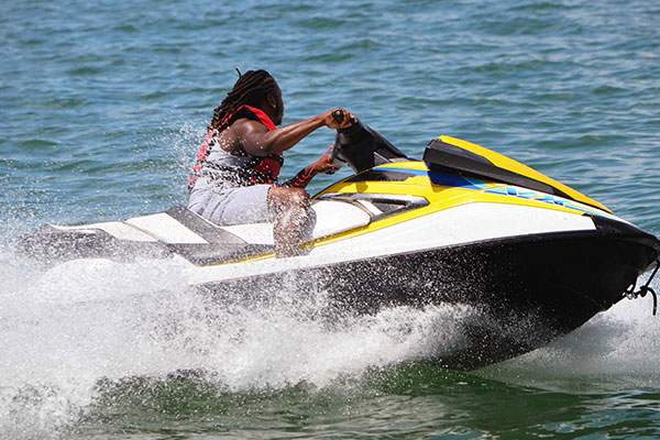 A person riding a yellow and black jet ski across the water.