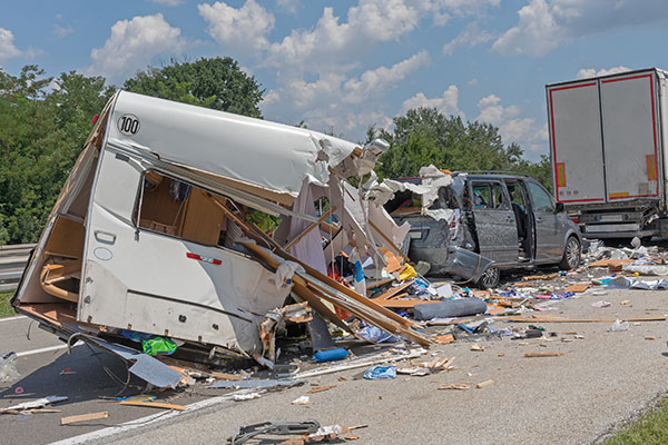 A destroyed trailer and damaged vehicle scattered across a highway after an accident.